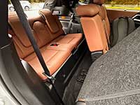 2026-Outlander-PHEV-seating - Etobicoke Voice Cargo area of a car with orange-brown leather rear seats folded down, gray carpeting, and a visible seat belt.